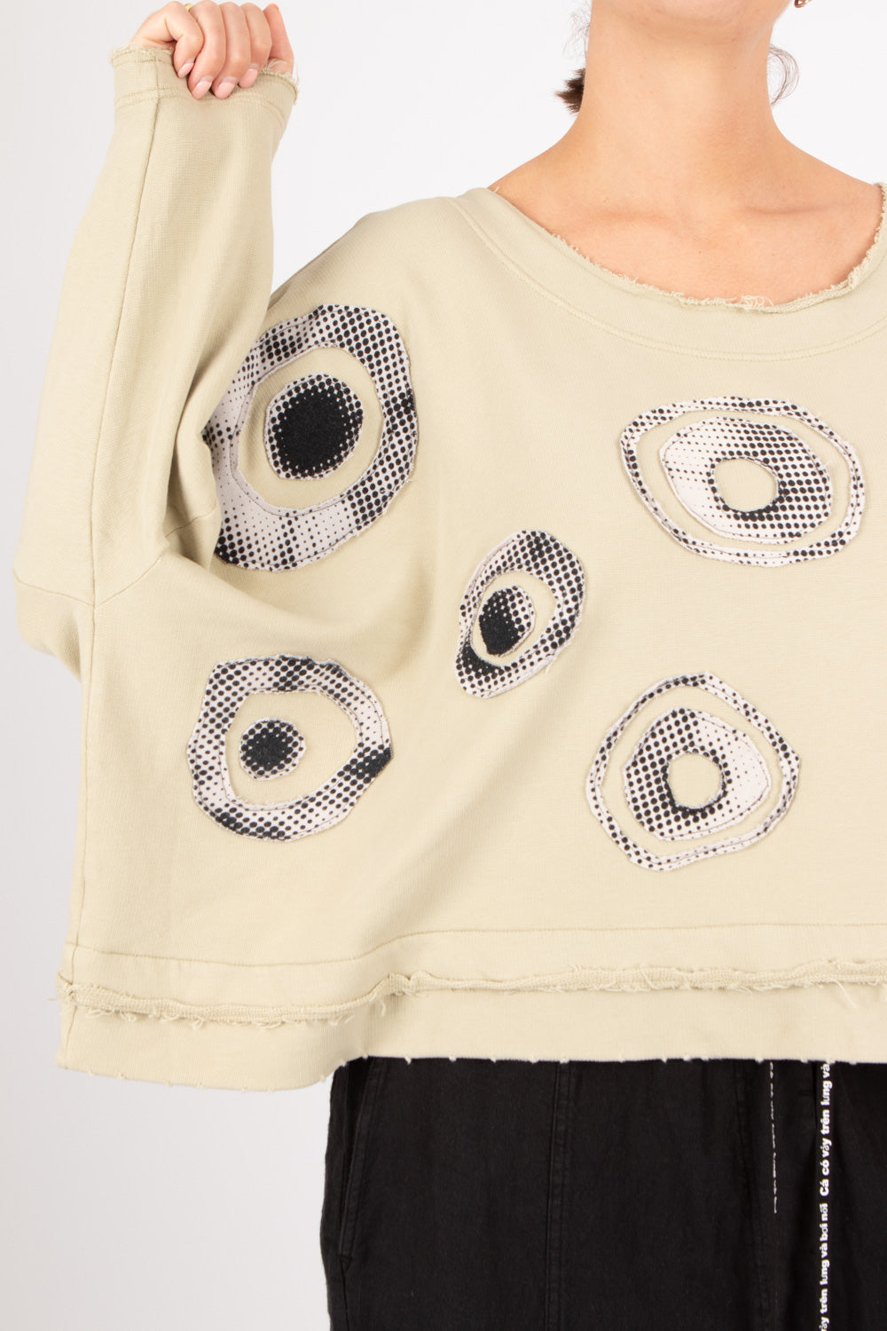 Beige sweater with circular patterns worn by a person on a light gray background