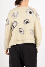 Beige sweater with black abstract patterns worn by a person on a white background