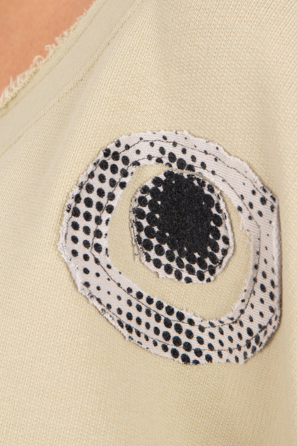 Close-up of a beige fabric with a black and white circular patterned patch.