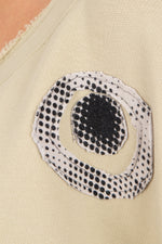 Close-up of a beige fabric with a black and white circular patterned patch.
